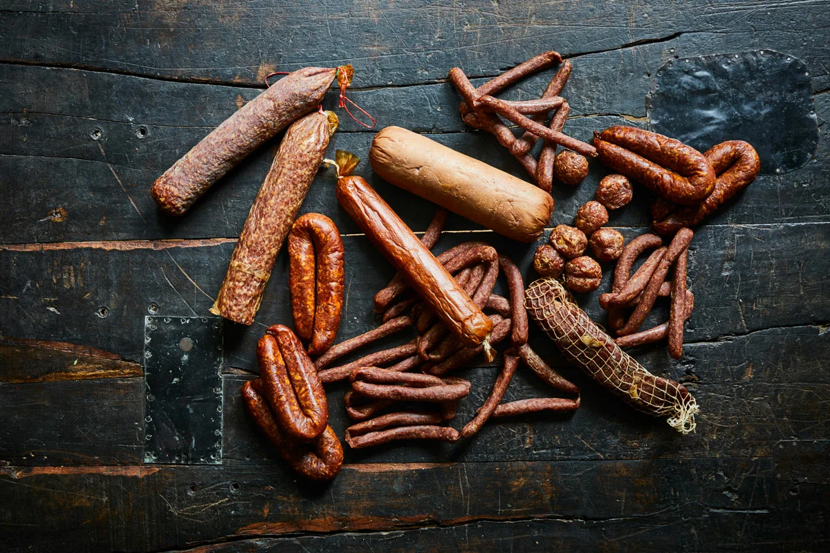 Different types of smoked sausages on a dark table