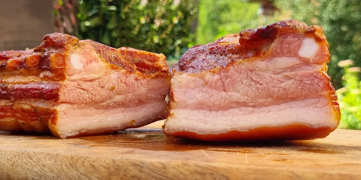 Smoked pork belly cut in half on a wooden board